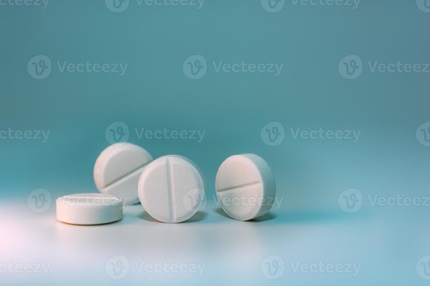 Several white pills on a blue-green background with turquoise. photo