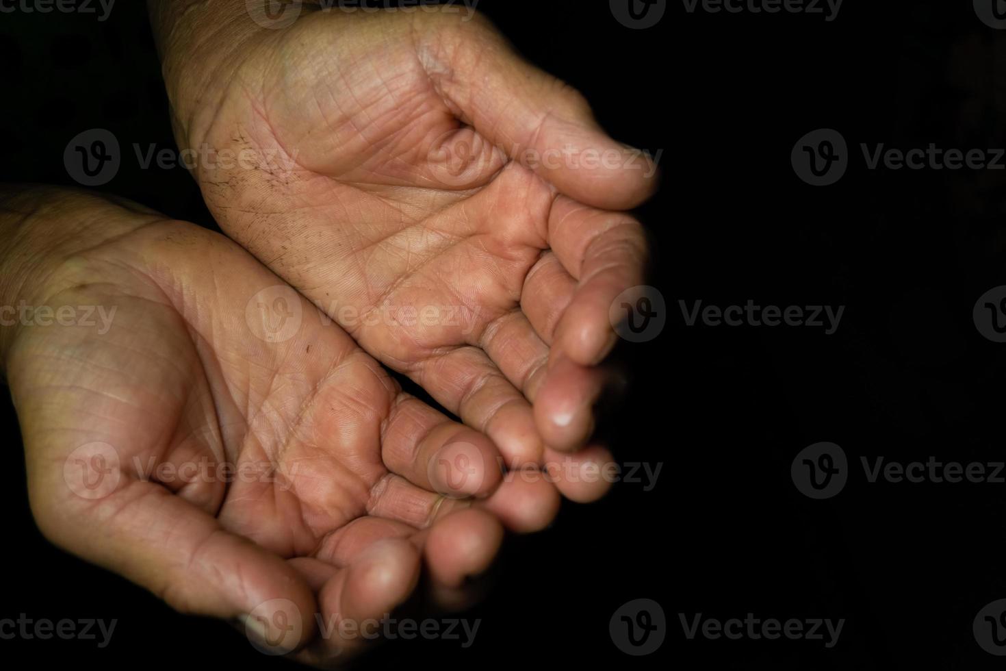 Close up, Two chubby hands with wrinkled palms towards the top of an old woman on a black background with copy space. photo
