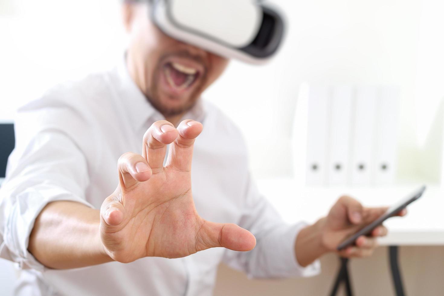 businessman wearing virtual reality goggles in modern office with mobile phone using with VR headset photo