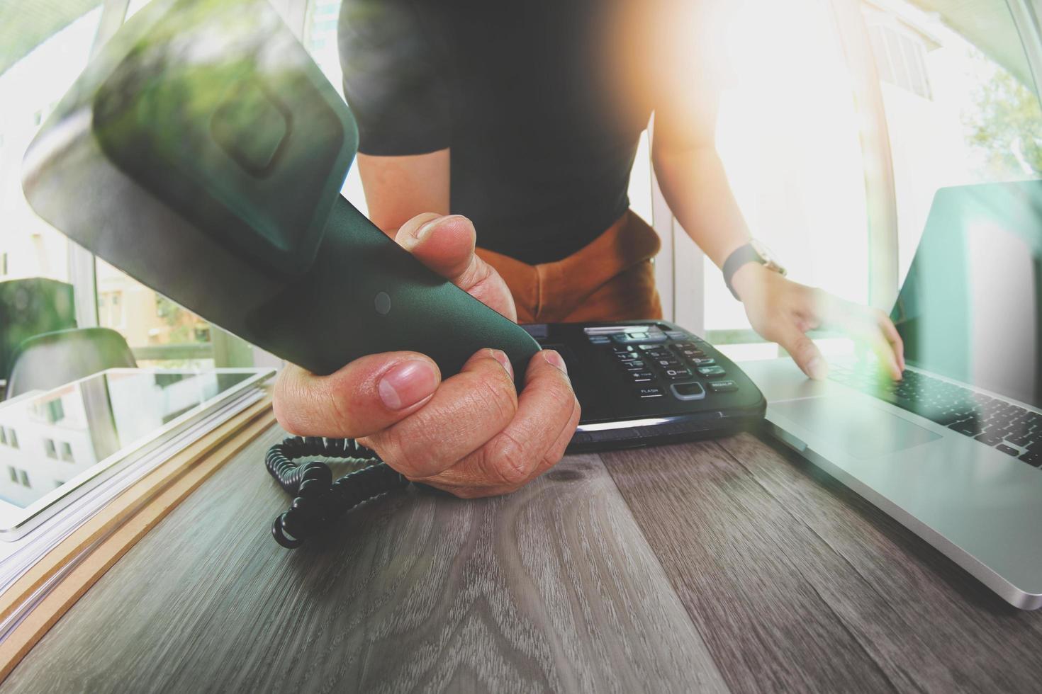 close up of designer hand holding telephone in the office as concept incoming call for you photo