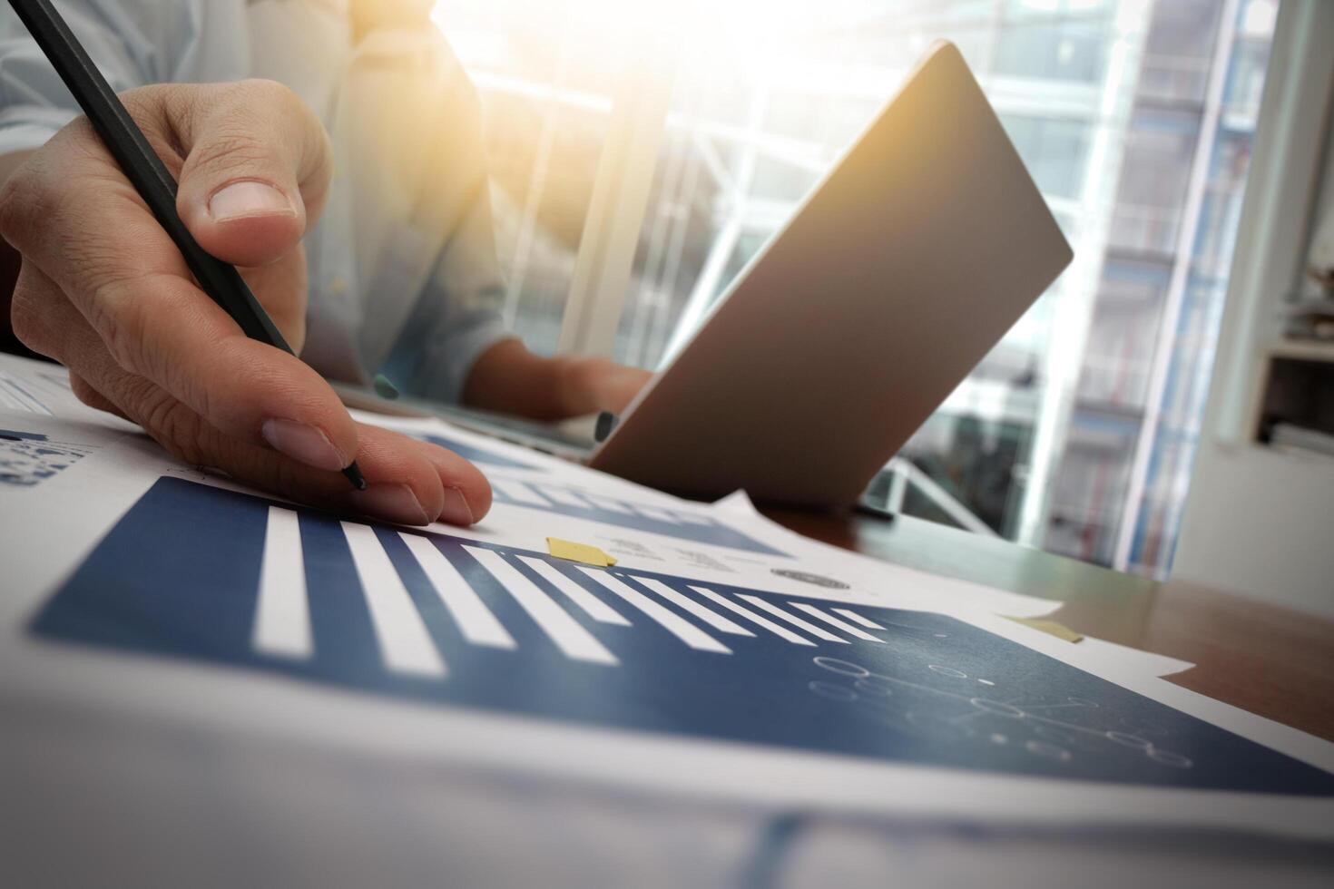 business documents on office table with smart phone and digital tablet and graph business diagram and man working in the background photo