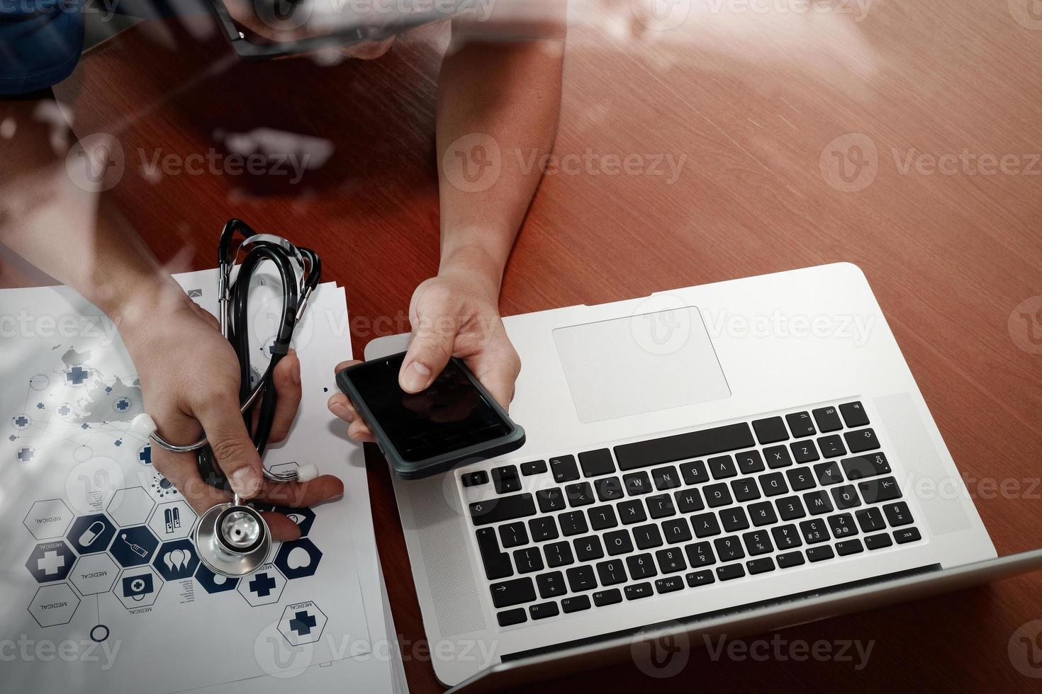 top view of Medicine doctor hand working with modern computer and smart phone on wooden desk as medical concept photo