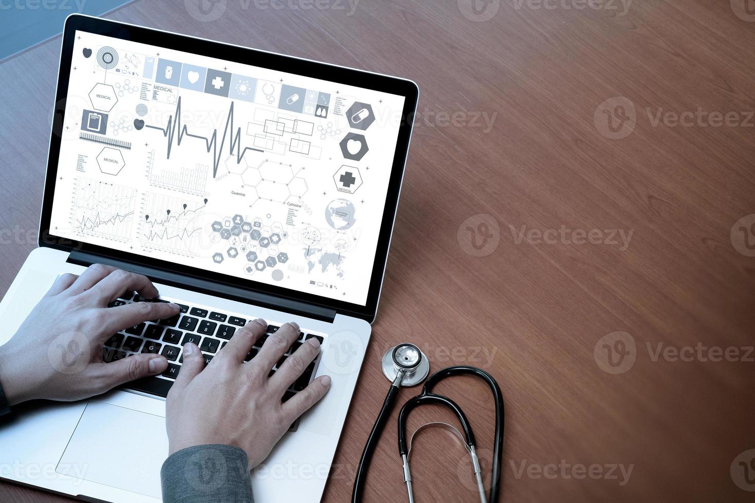 vista superior de la mano del médico que trabaja con una computadora moderna y una pantalla en blanco en un escritorio de madera como concepto médico foto