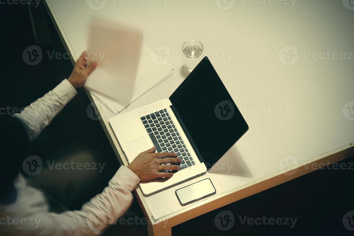 top view of man working with business documents on office table with digital tablet and man working with smart laptop computer photo