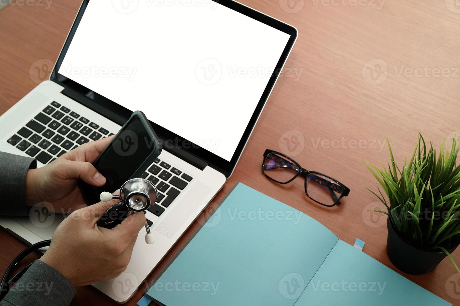 top view of Medicine doctor hand working with modern computer and smart phone with blank screen on wooden desk as medical concept photo