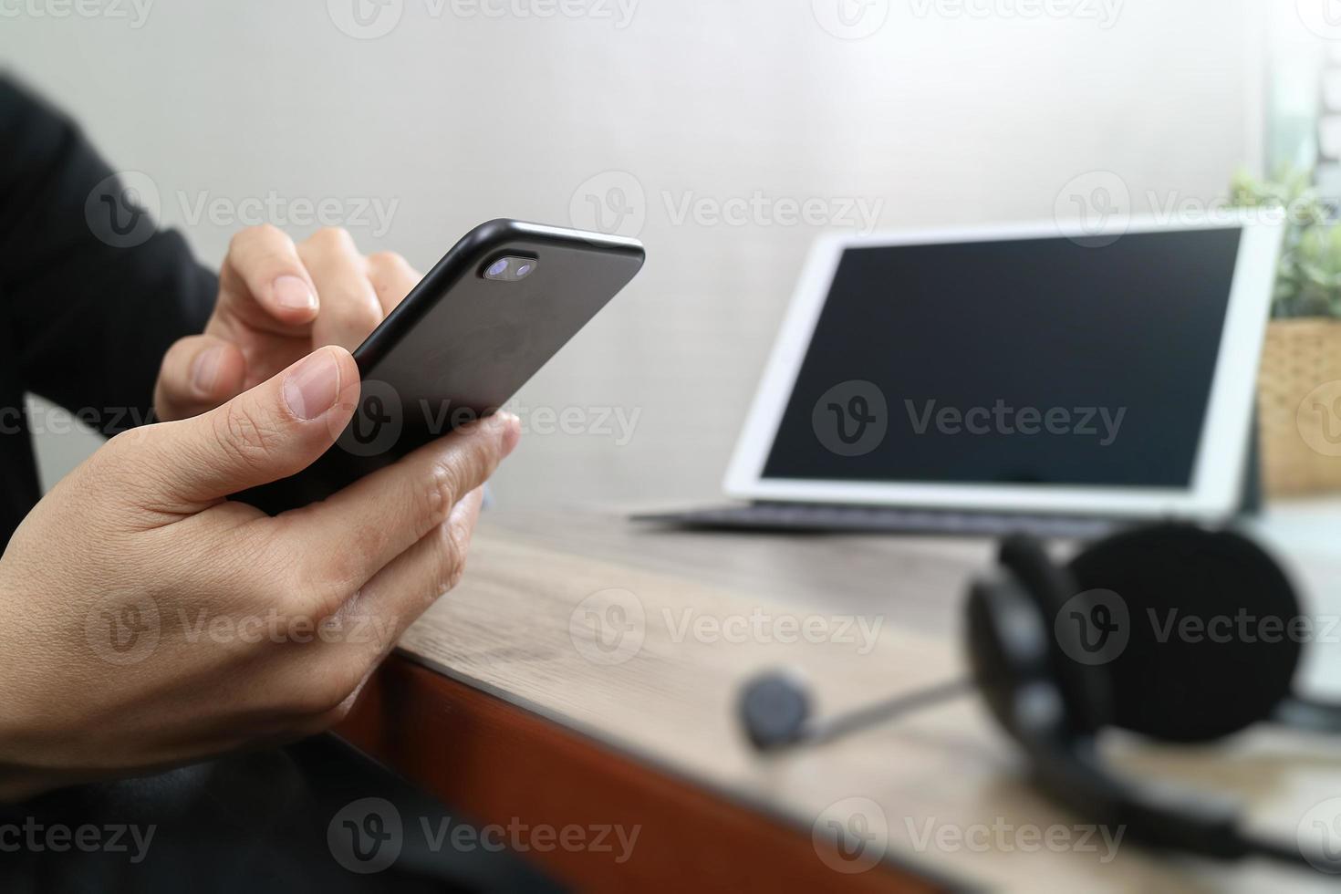 man hand using VOIP headset with digital tablet computer docking keyboard,smart phone,concept communication, it support, call center and customer service help desk on wooden table photo