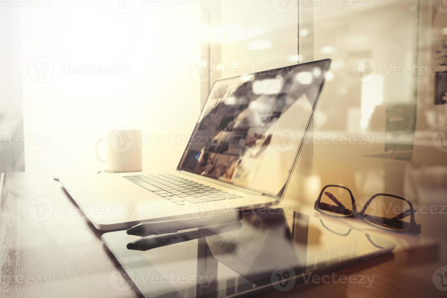 lugar de trabajo de oficina con computadora portátil y teléfono inteligente en la mesa de madera y fondo borroso de la ciudad de Londres foto