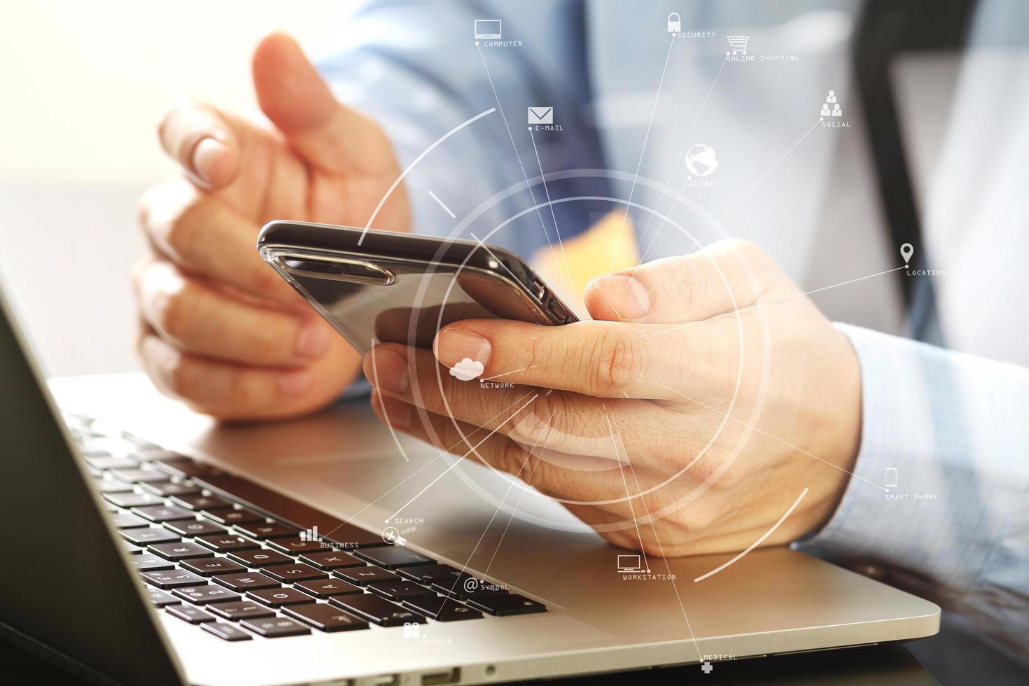 close up of businessman working with mobile phone and laptop computer on wooden desk in modern office photo