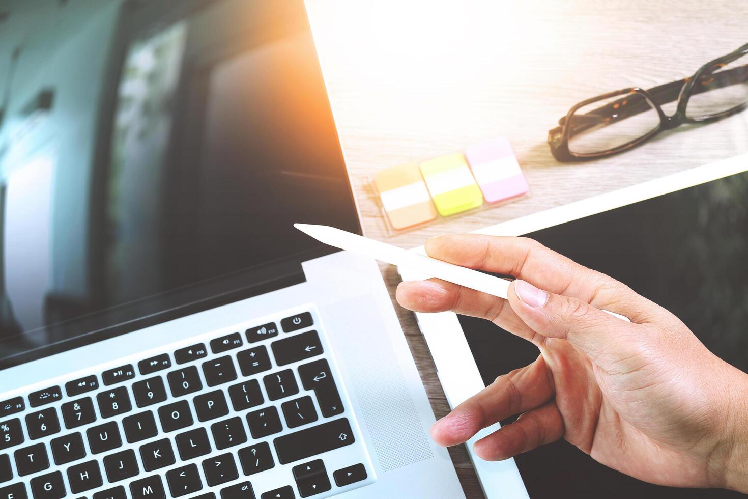 mano de hombre de negocios que trabaja con una tableta digital y una nota de memo y una computadora portátil con efecto de capa de estrategia de negocios digital en el escritorio de madera como concepto foto