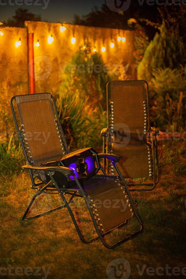 dos tumbonas de jardín con un altavoz de música en una de las sillas. descanso nocturno con música. foto