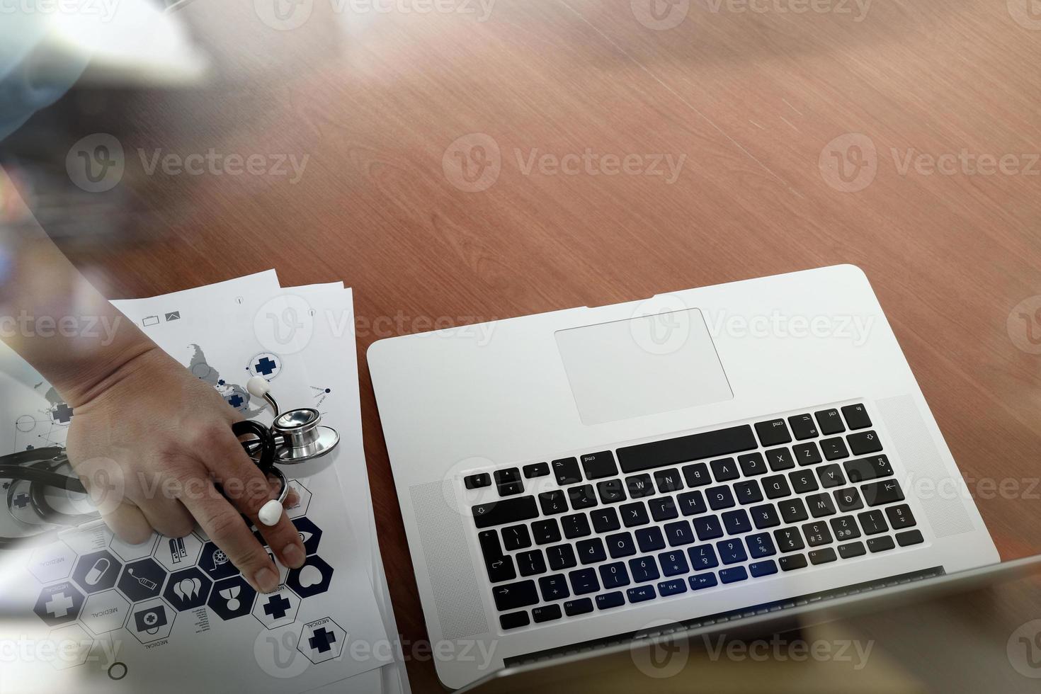 vista superior de la mano del médico que trabaja con una computadora moderna y un teléfono inteligente en un escritorio de madera como concepto médico foto