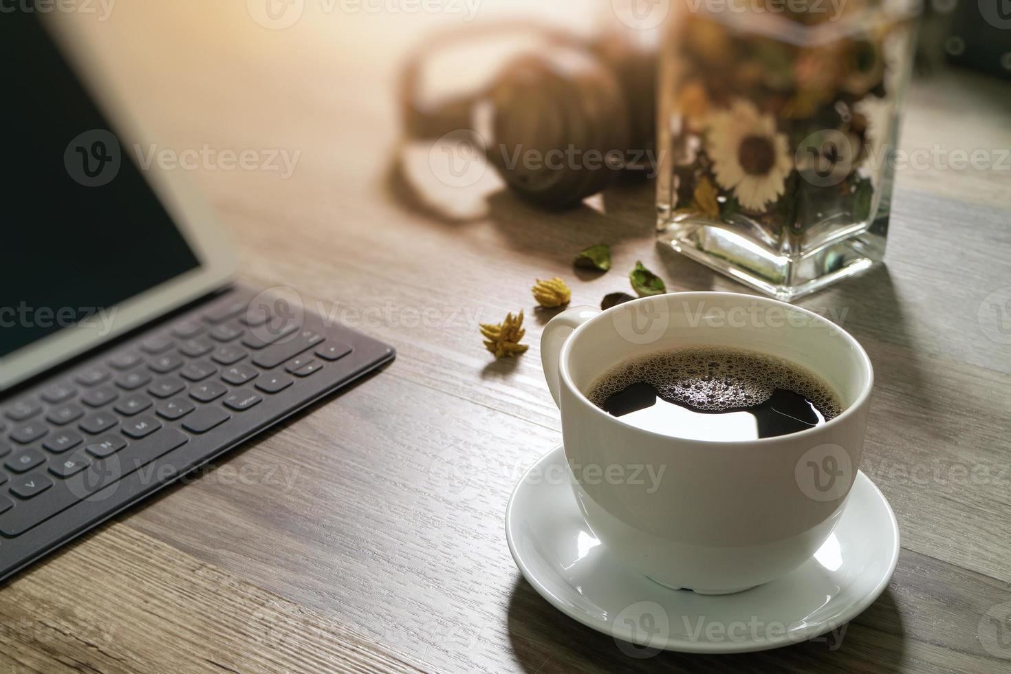 Coffee cup and Digital table dock smart keyboard,vase flower herbs,music headphone,eyeglasses on wooden table,filter effect photo