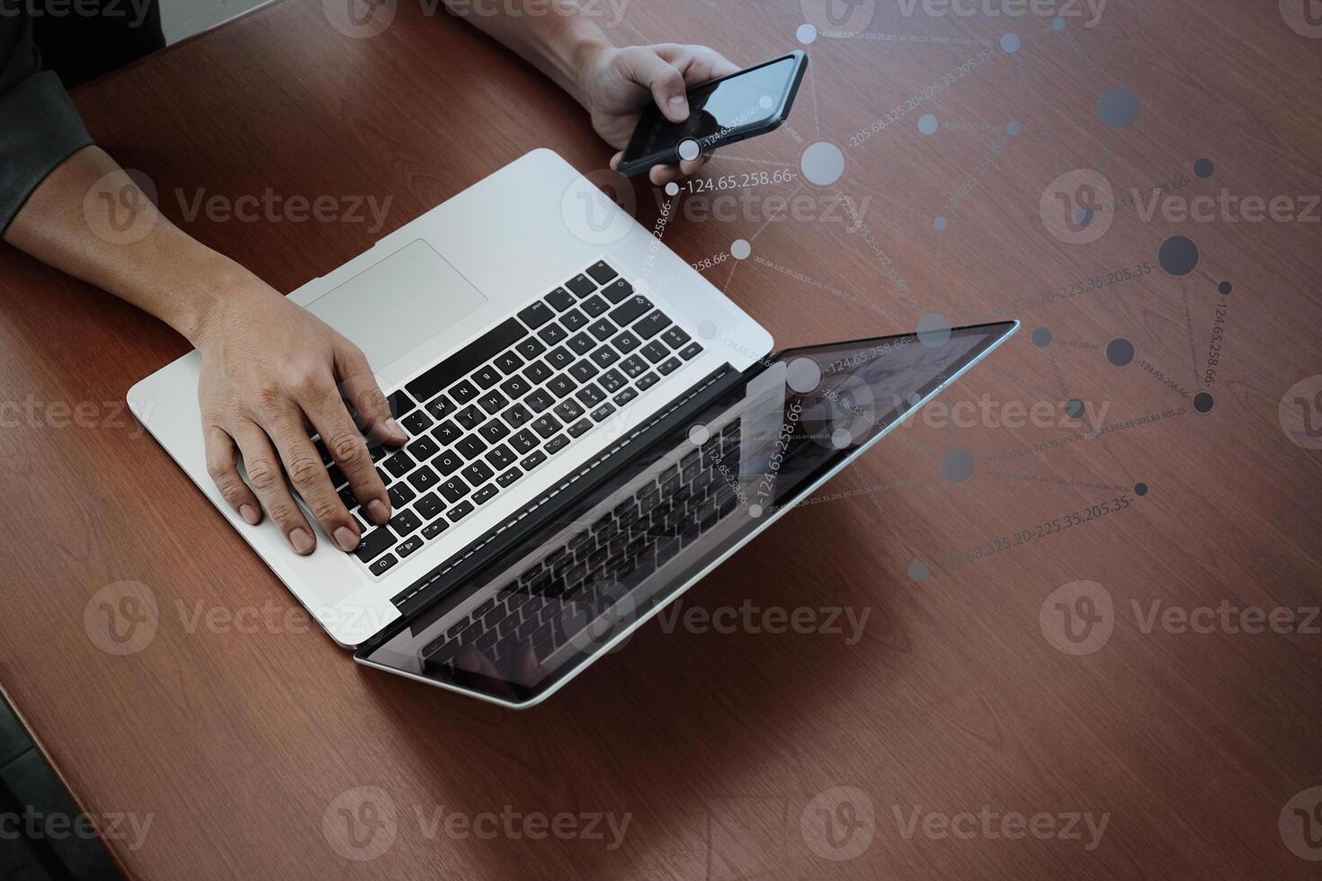 Vista superior de la mano del hombre de negocios trabajando con la nueva computadora moderna y teléfono inteligente y estrategia empresarial en el escritorio de madera como concepto foto