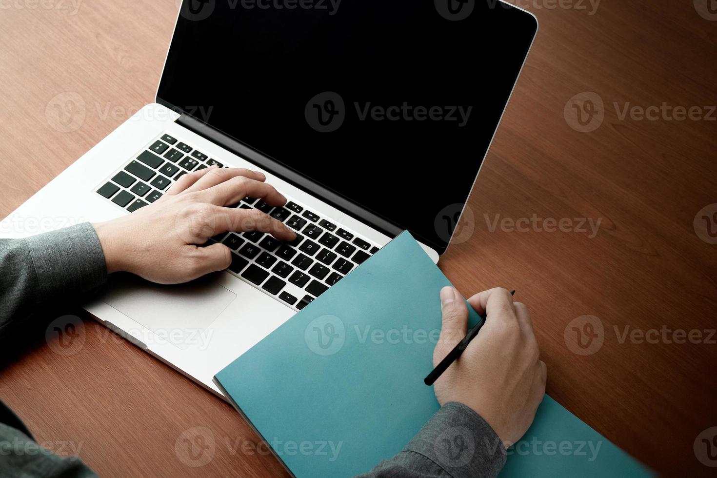 Vista superior de la doble exposición de la mano de un hombre de negocios que trabaja con una nueva computadora moderna y una estrategia empresarial y un libro en blanco como concepto foto