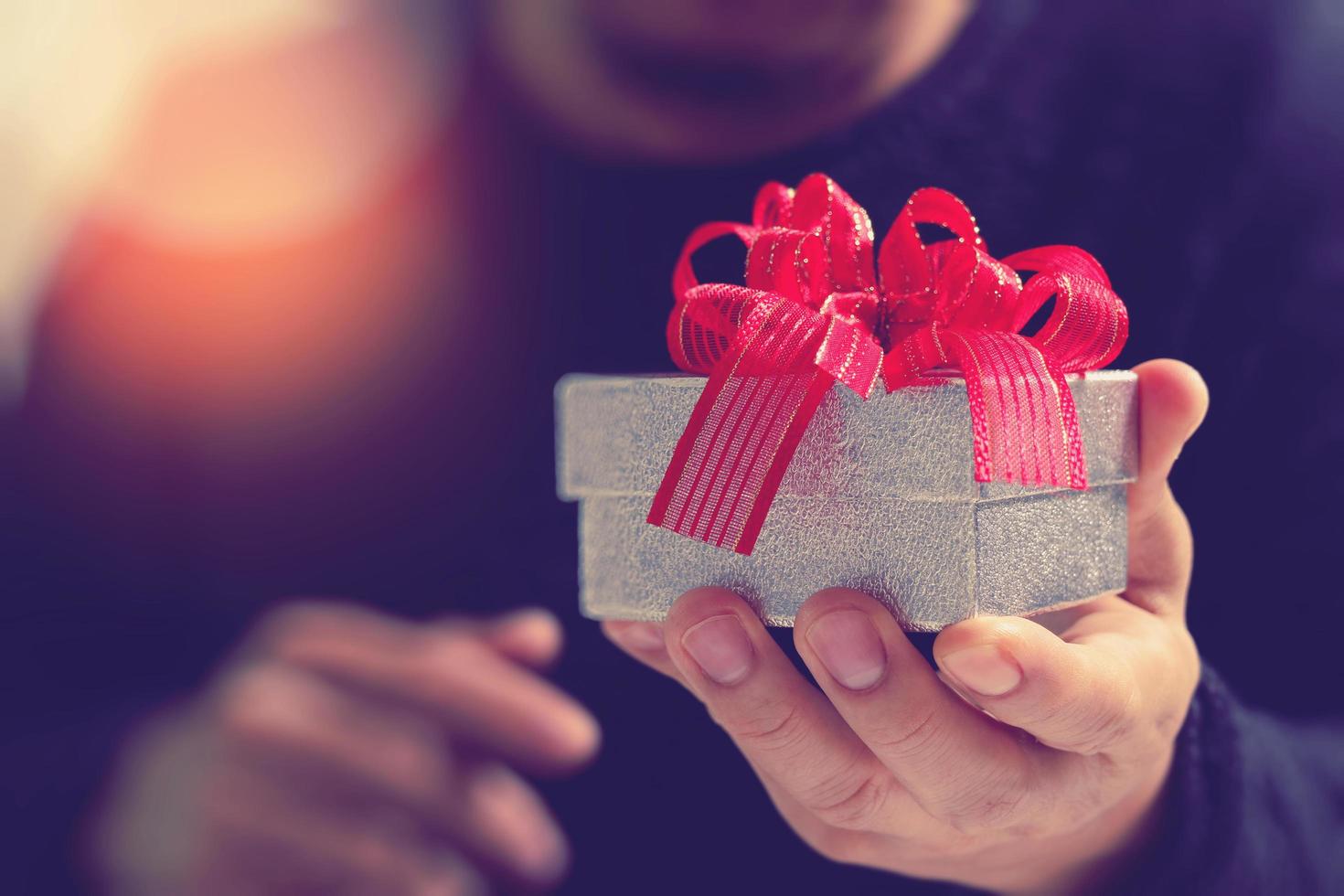 gift giving,man hand holding a gift box in a gesture of giving.blurred background,bokeh effect photo