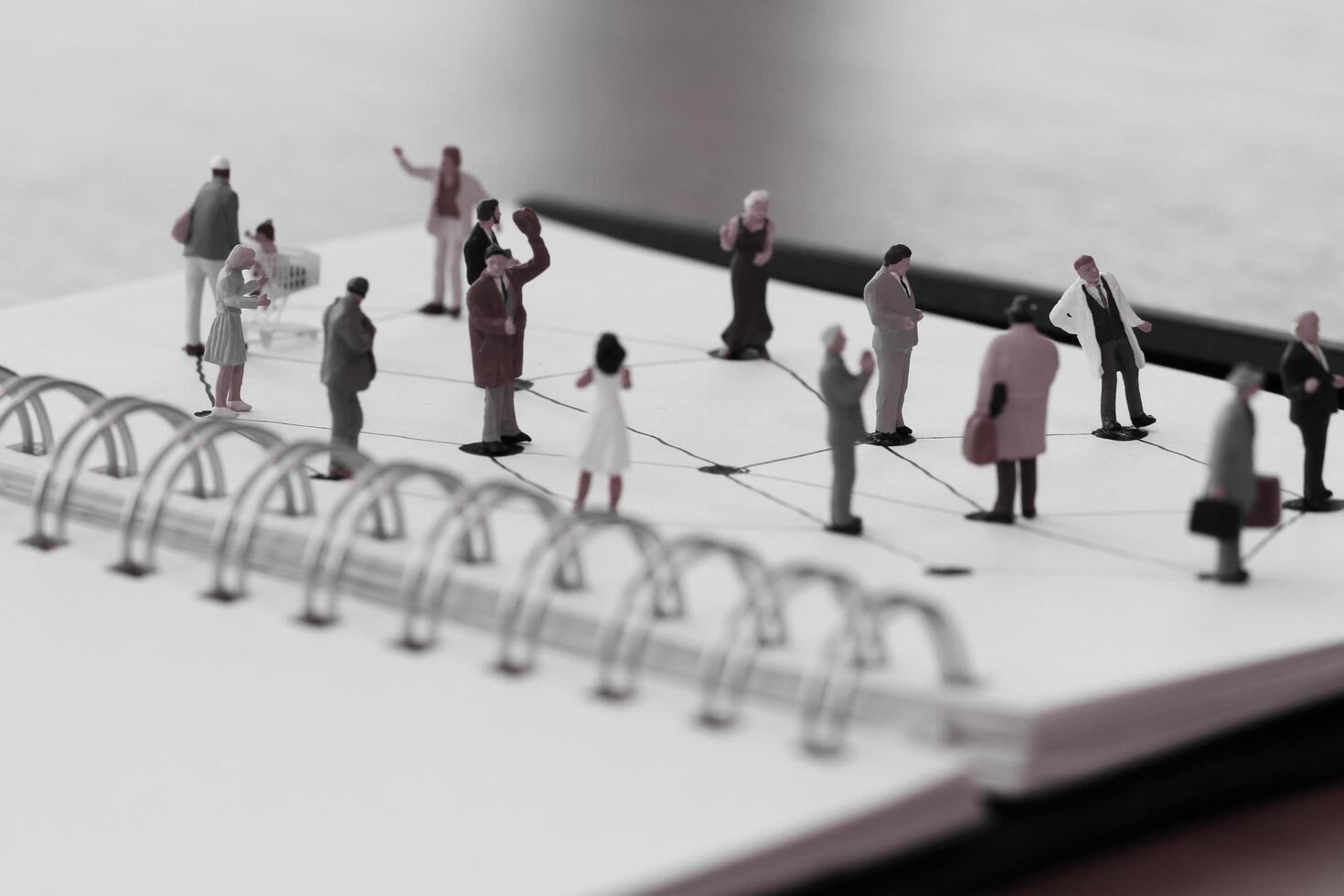 close up of miniature people with social network diagram on open notebook on wooden desk as social media concept photo