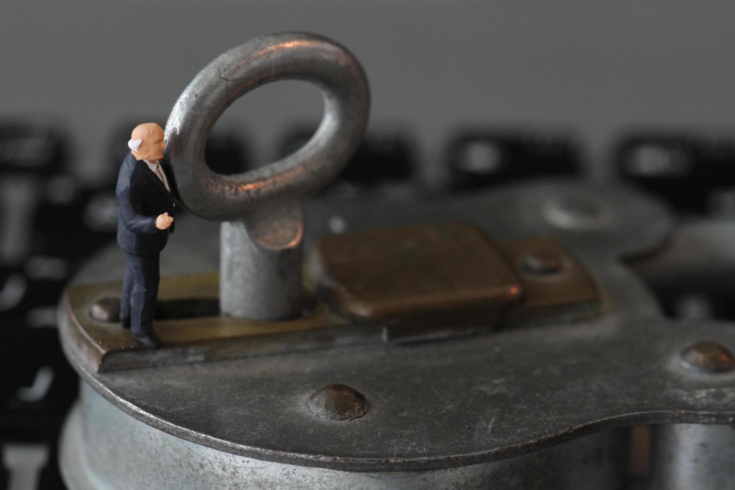 Internet security concept-miniature businessman stand on old key and padlock on laptop computer keyboard photo