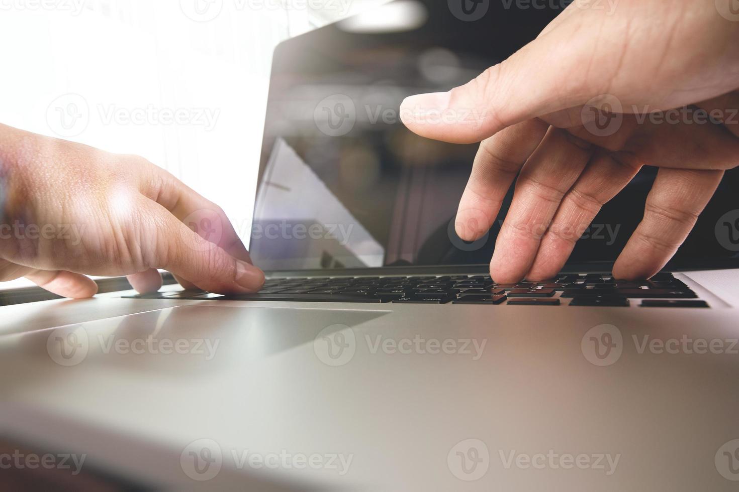 Cerca de la mano del hombre de negocios trabajando en la computadora portátil de pantalla en blanco en el escritorio de madera como concepto foto