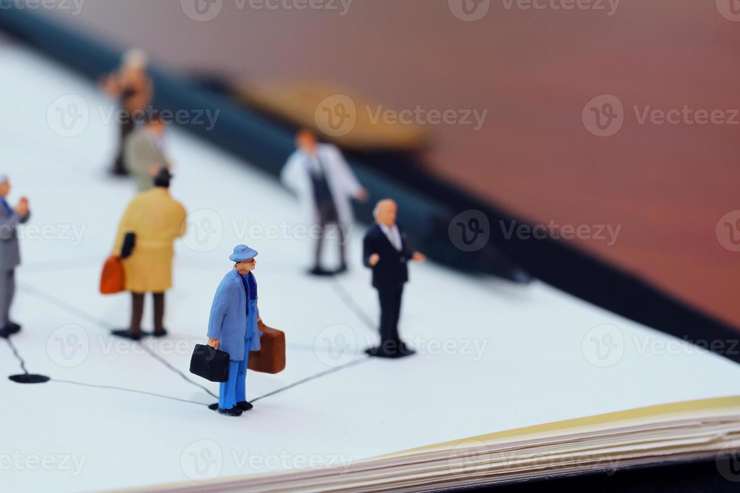 close up of miniature people with social network diagram on open notebook on wooden desk as social media concept photo