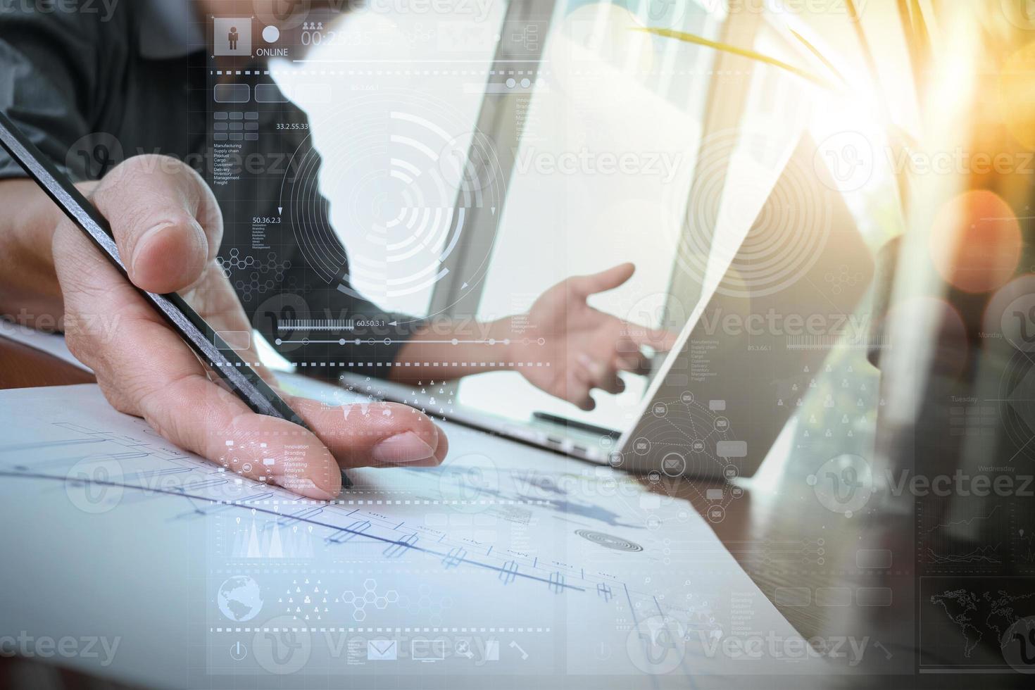 businessman hand working with new modern computer and business strategy documents with green plant and glass of water foreground on wooden desk in office photo