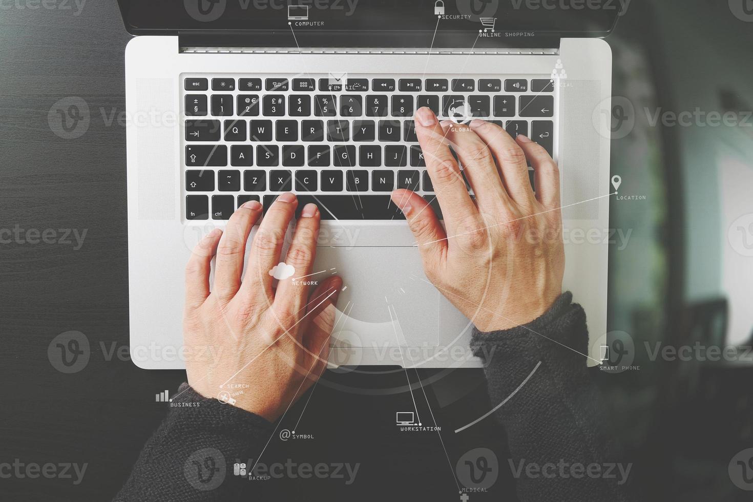 top view of businessman typing keyboard with laptop computer on wooden desk in modern office with virtual reality icon diagram photo