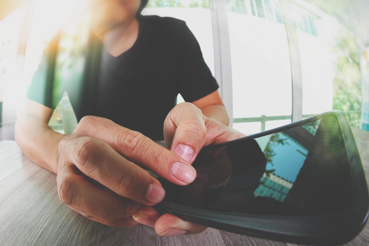 designer hand working and smart phone on wooden desk in office photo