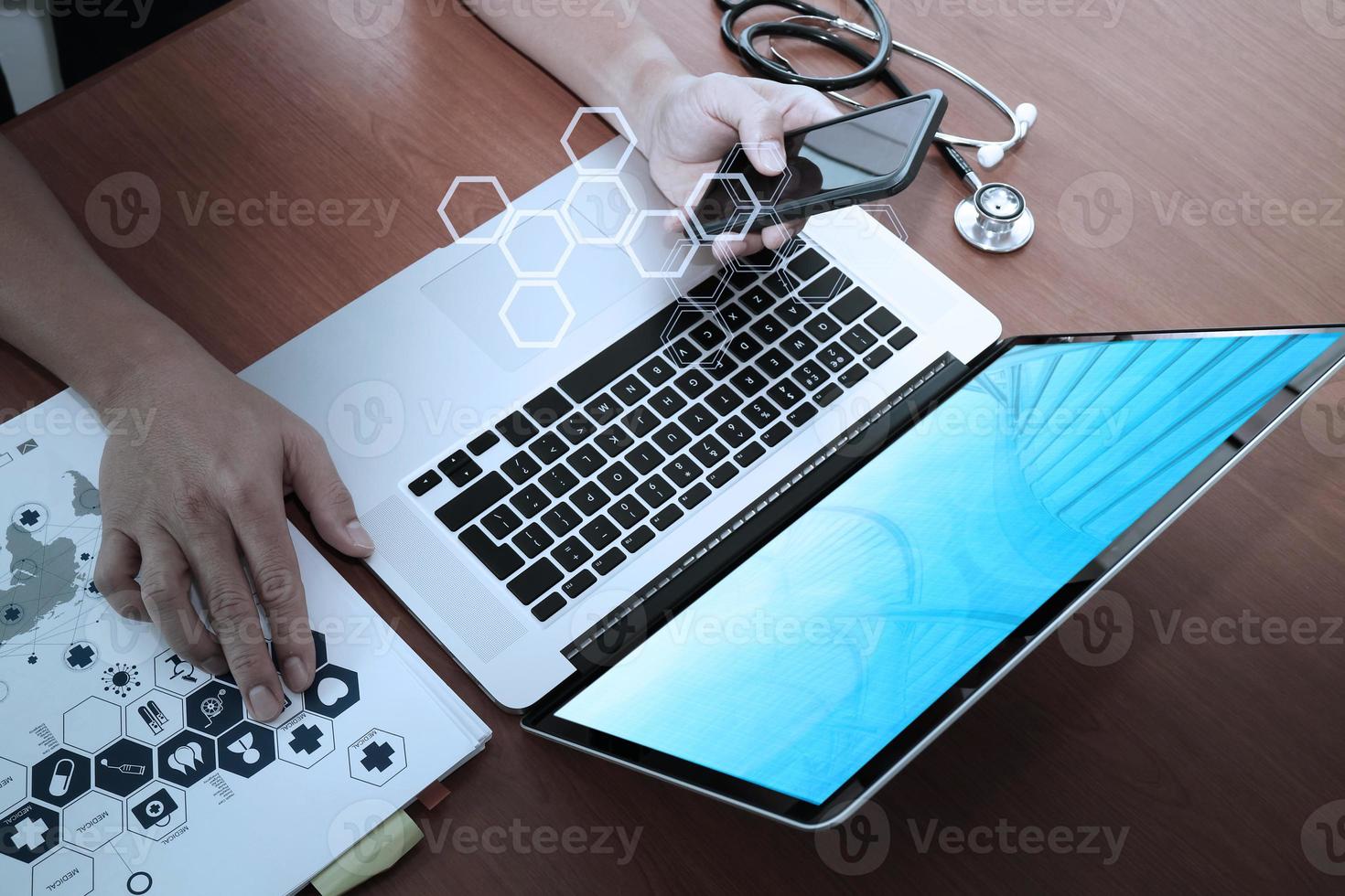 top view of Medicine doctor hand working with modern computer and smart phone on wooden desk as medical concept photo