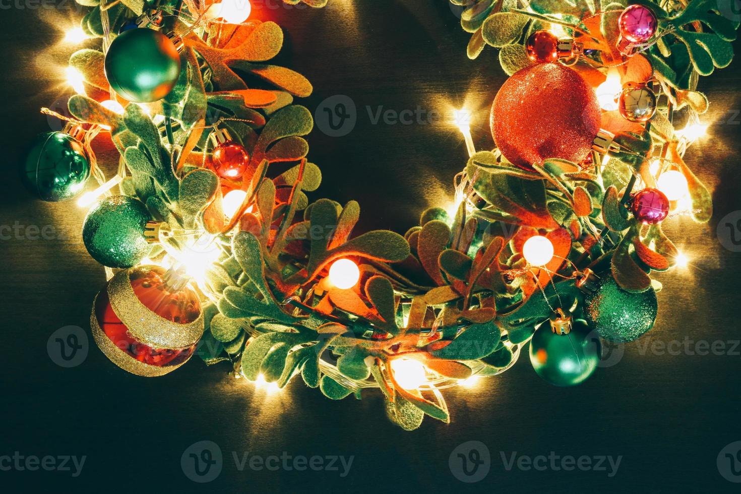 Greeting Season concept.Christmas wreath with decorative light on dark wood background photo