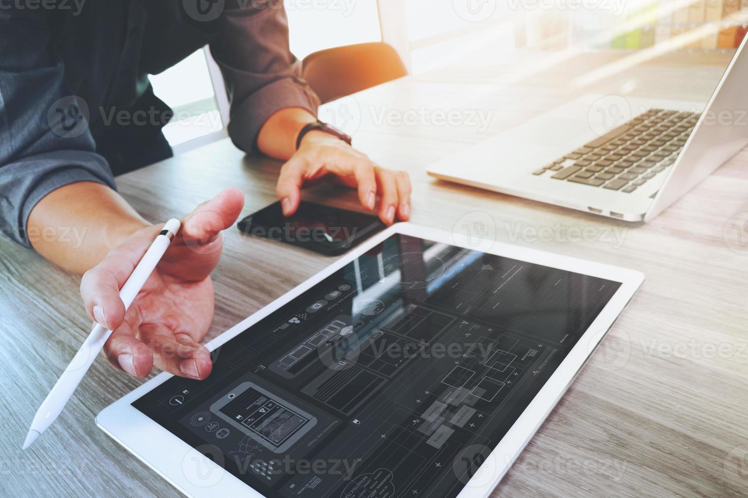 diseñador de sitios web que trabaja con tableta digital y computadora portátil y diagrama de diseño digital en un escritorio de madera como concepto foto