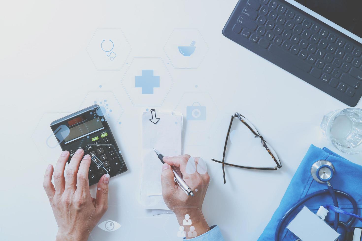 top view of Healthcare costs and fees concept.Hand of smart doctor used a calculator for medical costs in modern hospital with VR icon diagram photo