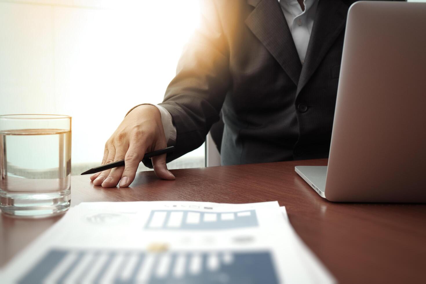 business documents on office table with smart phone and digital tablet and graph business diagram and man working in the background photo