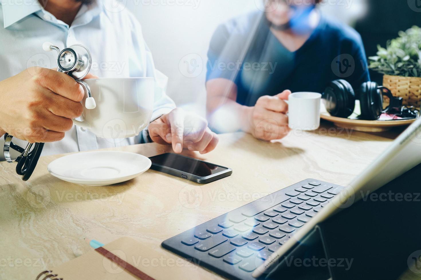 Medical doctor team taking coffee break.using digital tablet docking smart keyboard and smart phone on marble desk.listen music,filter film effect photo