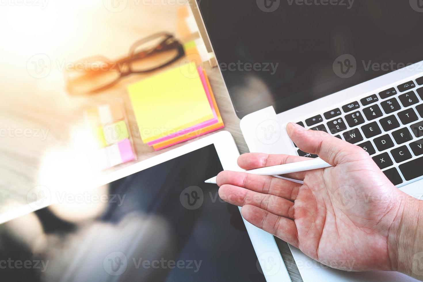 businessman hand working with digital tablet computer and memo note and laptop computer with digital business strategy layer effect on wooden desk as concept photo