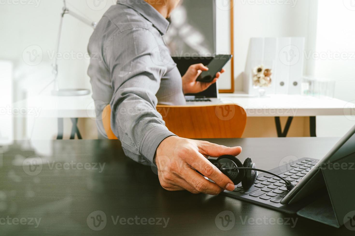 businessman using VOIP headset with digital tablet computer and smart phone,as concept communication and call center or customer service help desk in modern office photo