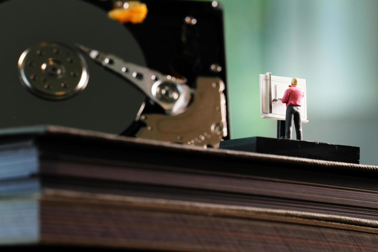 concepto de big data: ingeniero en miniatura que trabaja con una mesa de dibujo con fondo de disco duro abierto foto