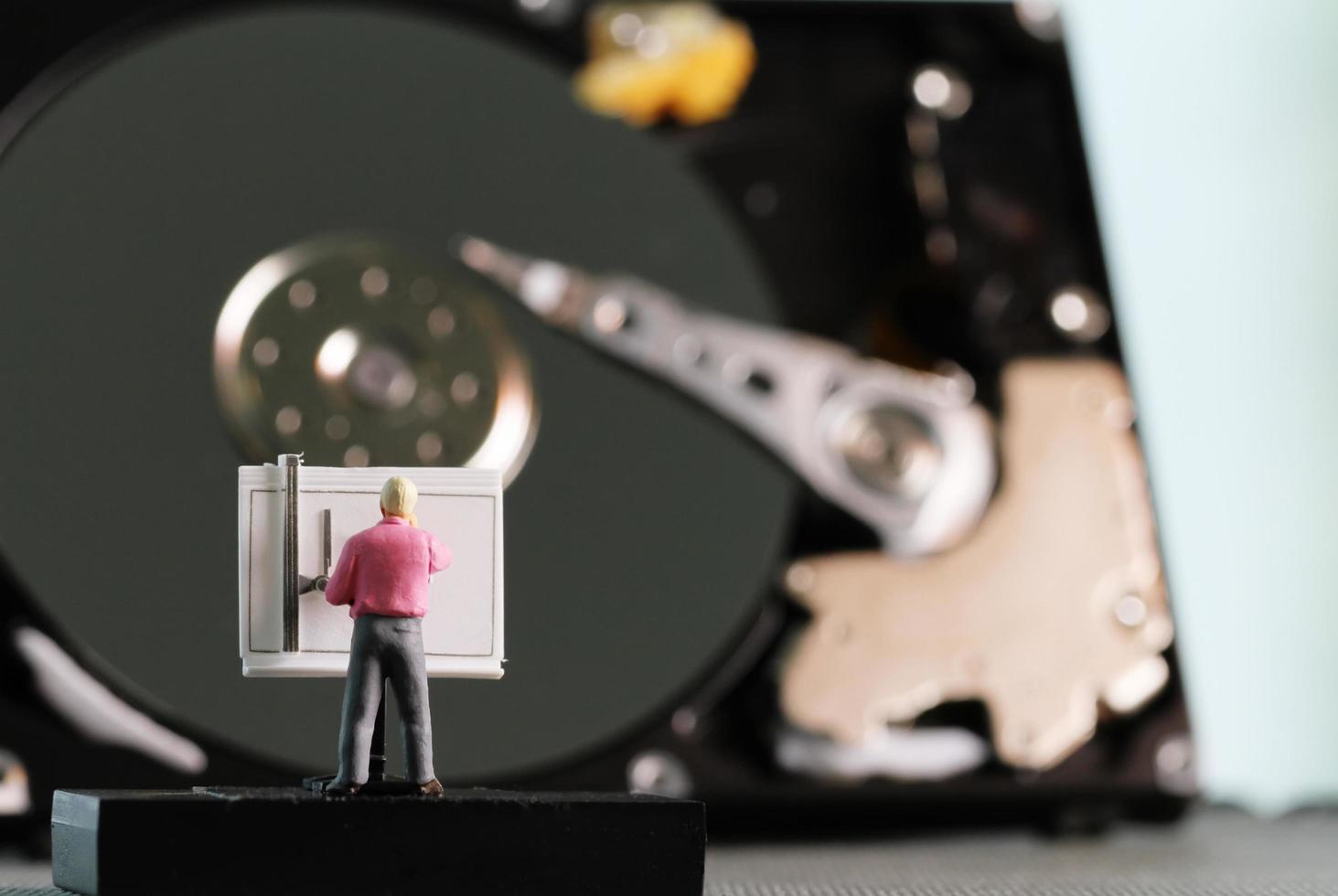 Big data concept-miniature engineer working wirh drafting table with open harddisk background photo