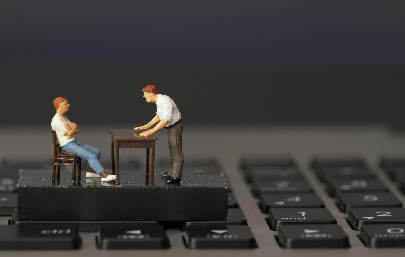 working online concept-miniature businessman boss angry with employee on laptop computer photo