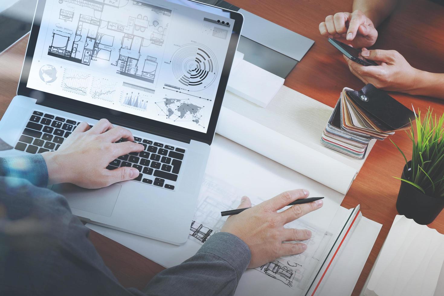 top view of two colleagues interior designers discussing data with new modern computer laptop and pro digital tablet with sample material on wooden desk as concept photo