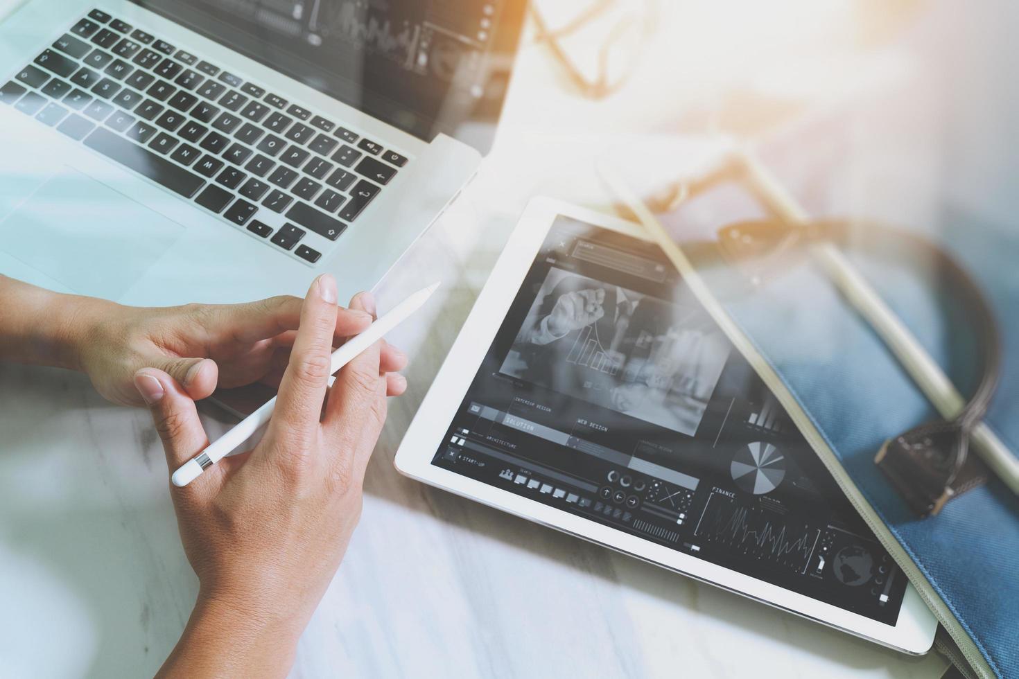 businessman hand working with digital tablet computer and smart phone and laptop computer with business bag on marble desk as concept. Top view, Sun flare effect photo