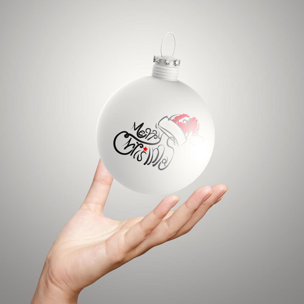 mano mostrando feliz navidad en bola de adorno foto