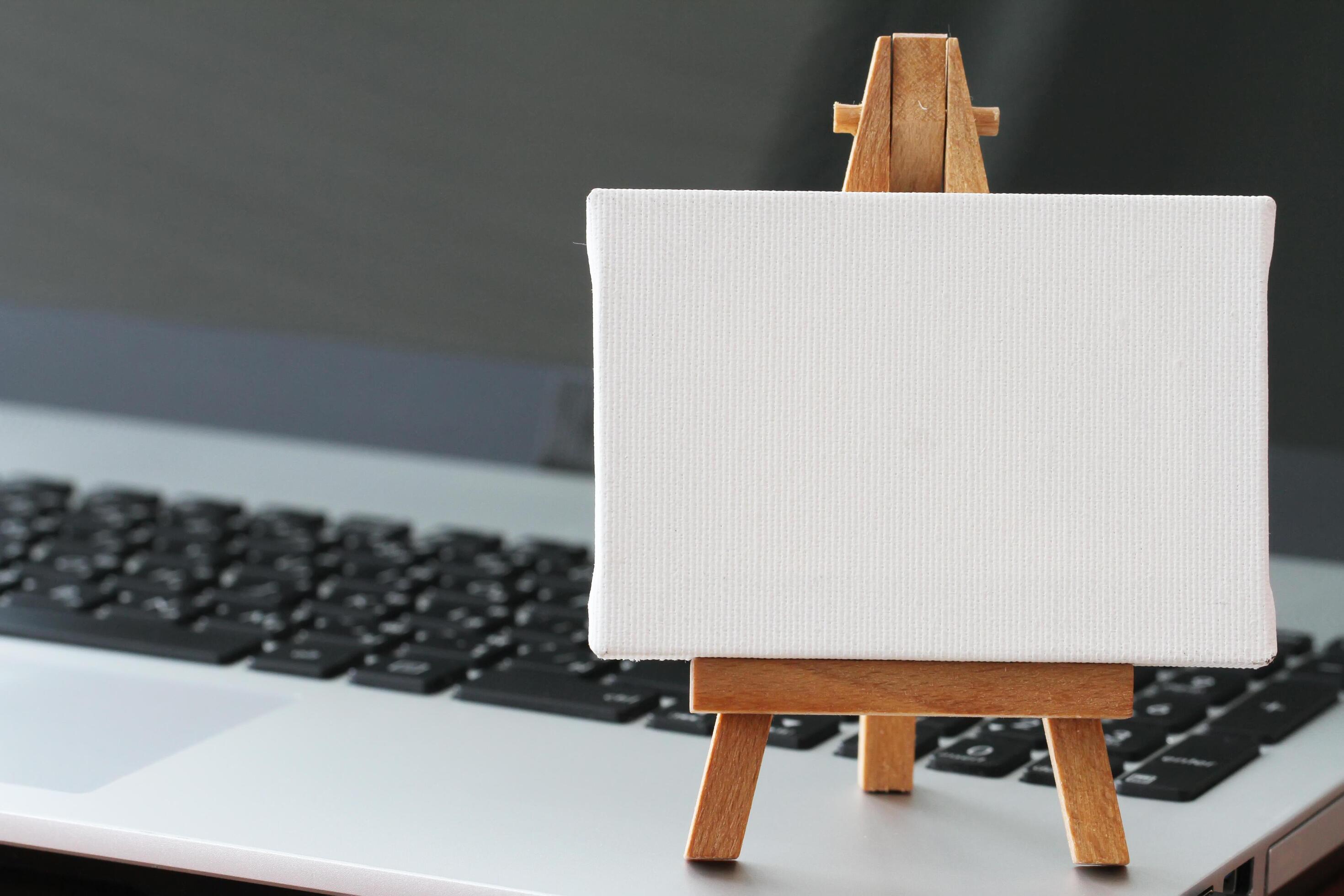 blank canvas and wooden easel on laptop computer as concept 5323049