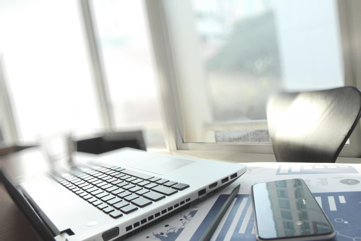 documentos de negocios en la mesa de la oficina con computadora portátil y teléfono inteligente como concepto de negocio de espacio de trabajo foto