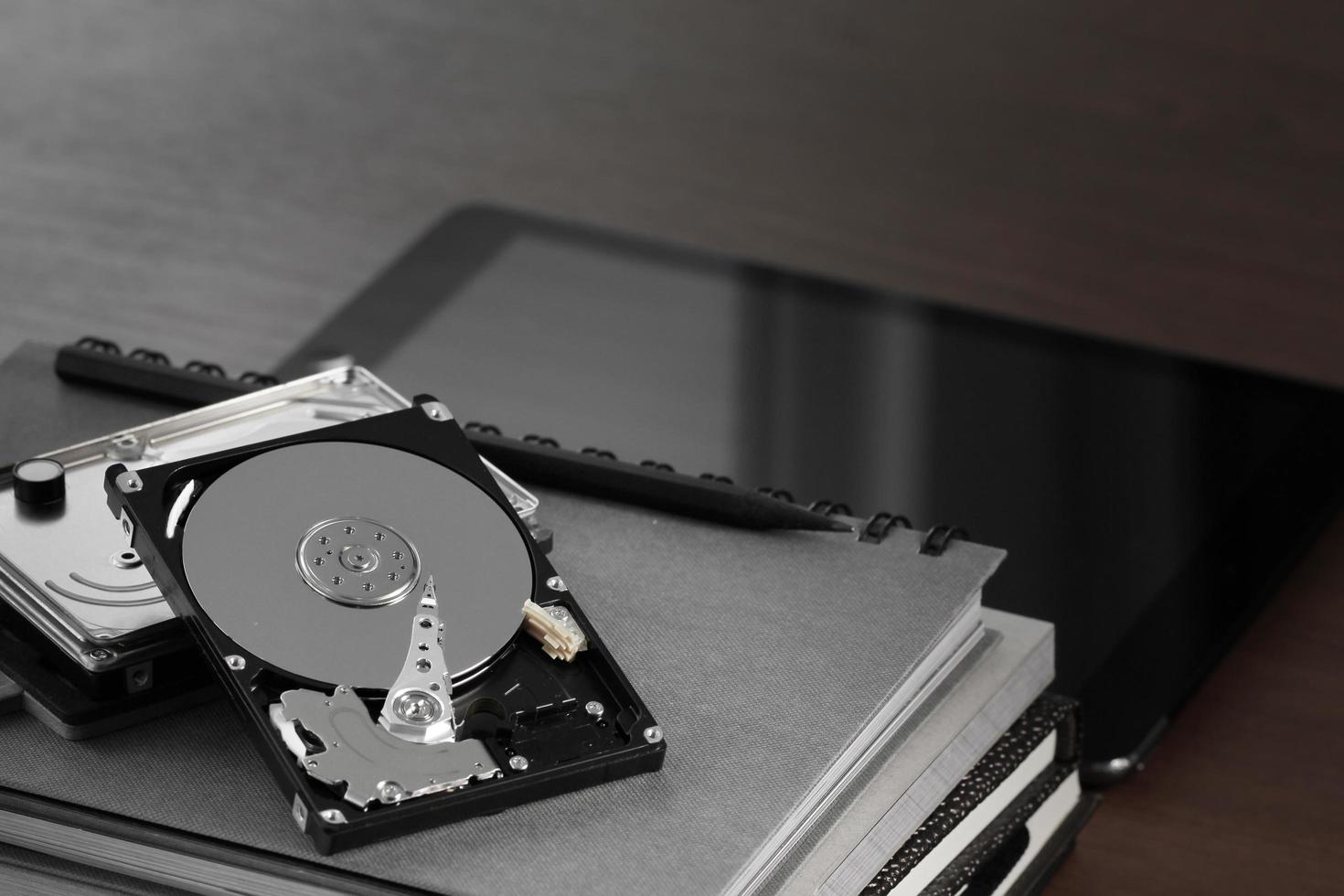 Close up of open computer hard disk drive on desk and notebook photo