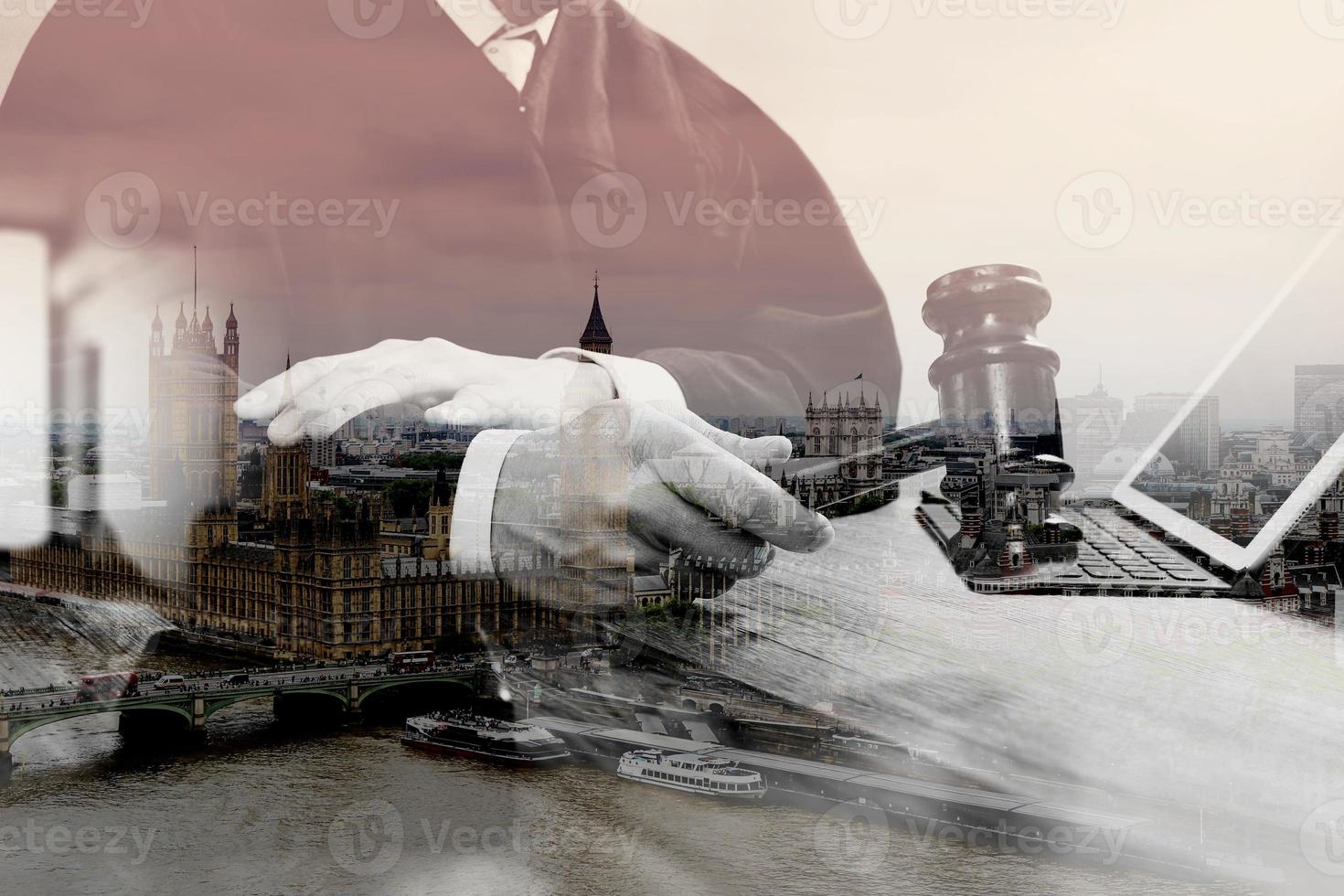 double exposure of justice and law concept.Male judge in a courtroom with the gavel,working with digital tablet computer docking keyboard on wood table,eyeglass,London architecture city photo