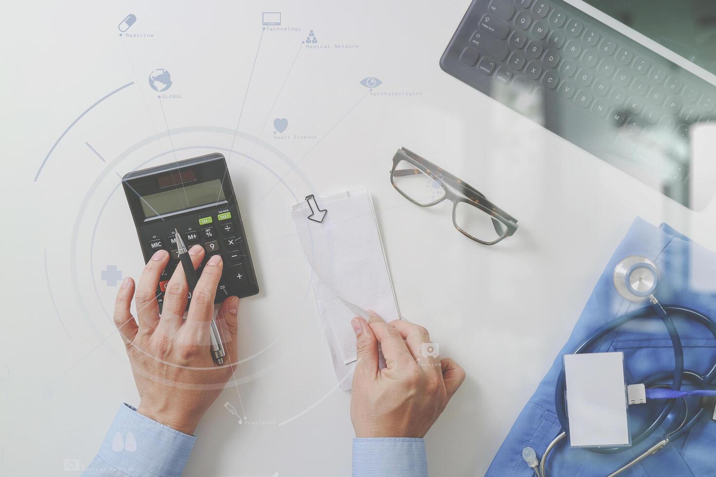 top view of Healthcare costs and fees concept.Hand of smart doctor used a calculator for medical costs in modern hospital with VR icon diagram photo