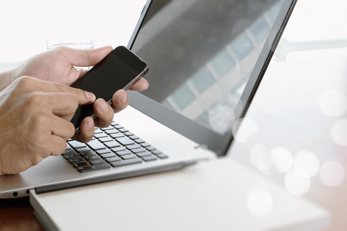 Businessman hand using laptop and mobile phone in office photo