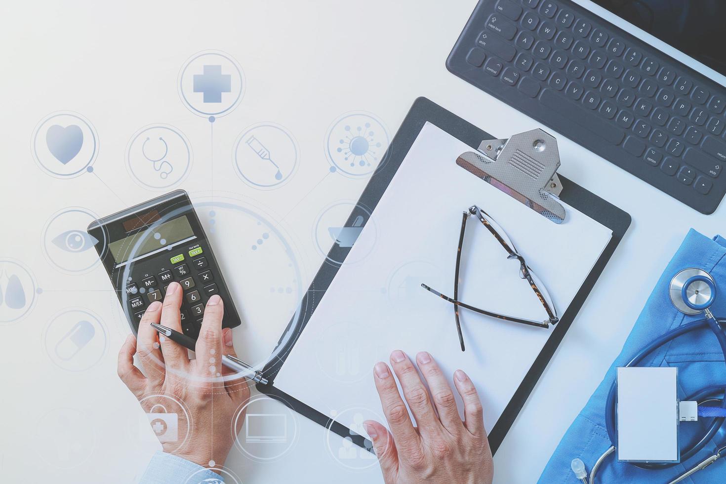 top view of Healthcare costs and fees concept.Hand of smart doctor used a calculator for medical costs in modern hospital with VR icon diagram photo