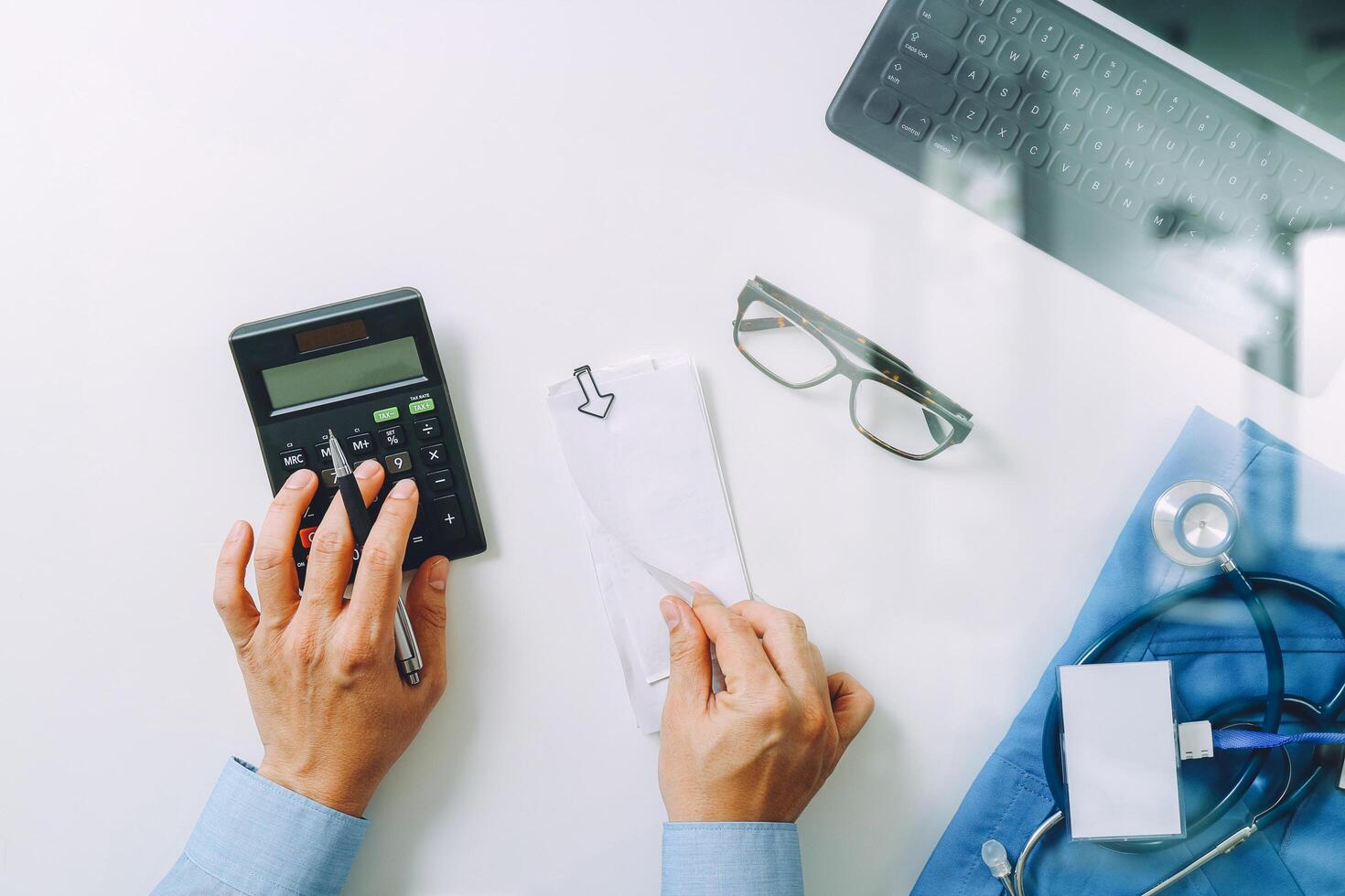 top view of Healthcare costs and fees concept.Hand of smart doctor used a calculator for medical costs in modern hospital photo