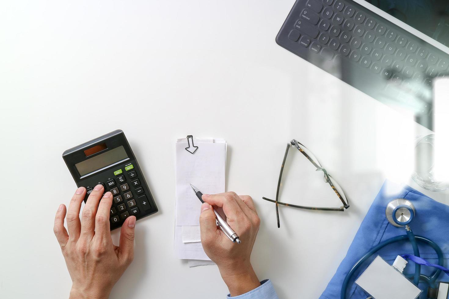 top view of Healthcare costs and fees concept.Hand of smart doctor used a calculator for medical costs in modern hospital photo