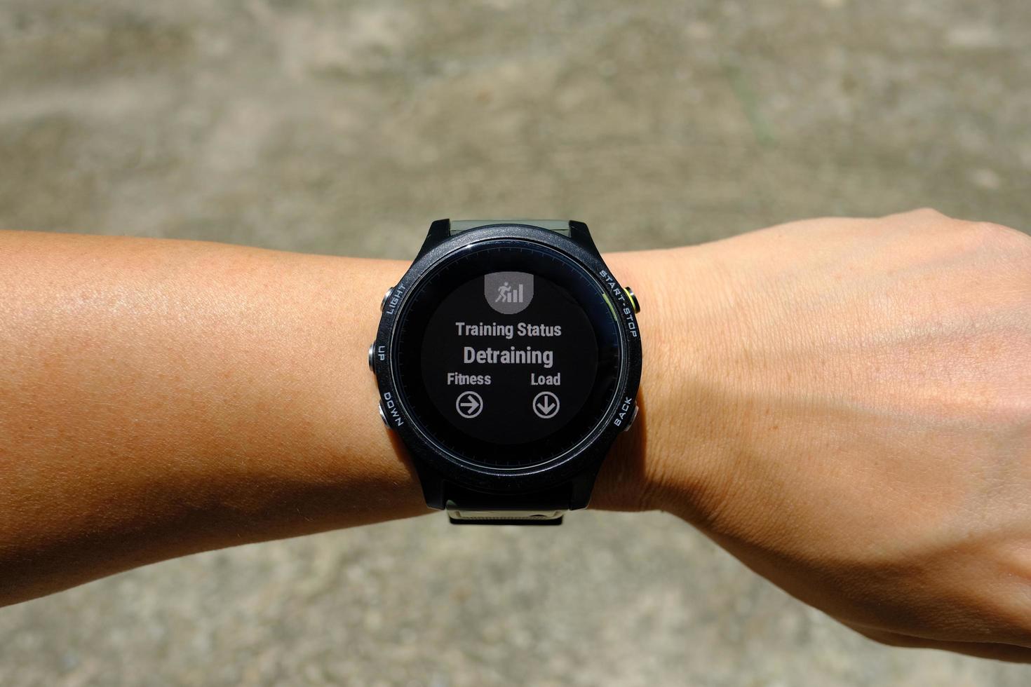 Training status on modern round-faced GPS multisport digital smartwatch on left hand wrist, detraining means decreasing load of training, selective focus photo